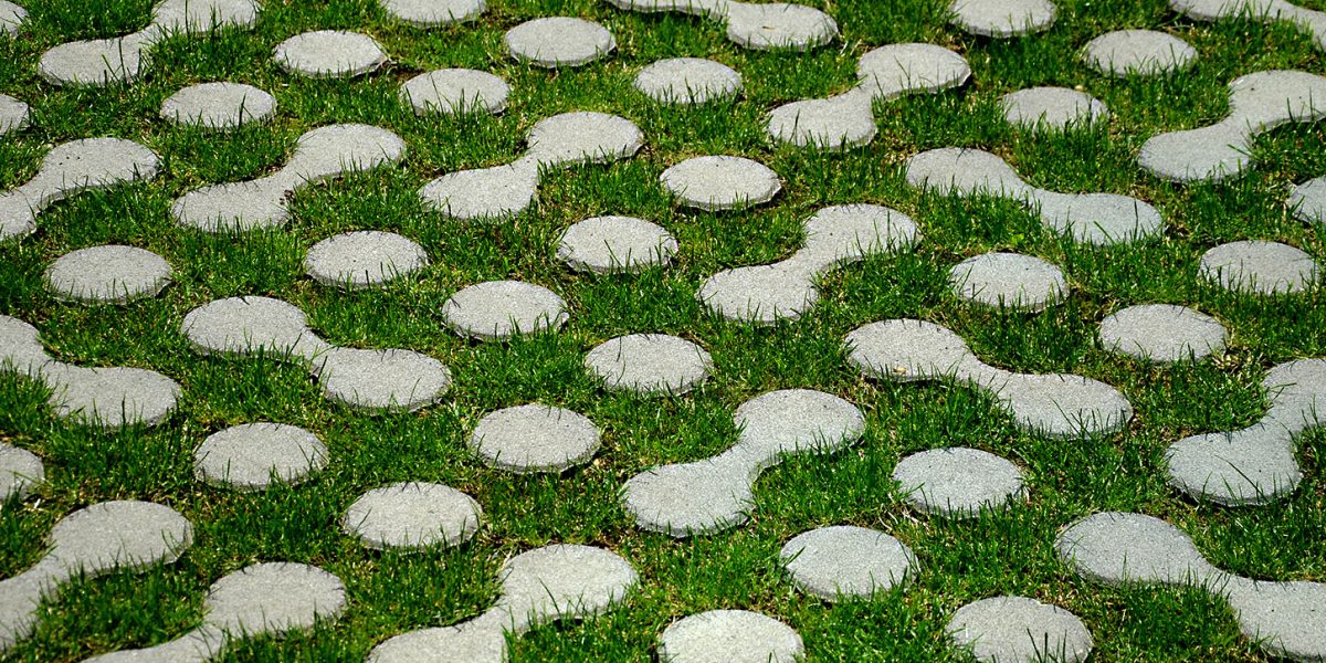 grass pavers block tiles made of concrete in the shape of connected circles amoeba gray shape repeating in a grid serving the crossing of people across the lawn