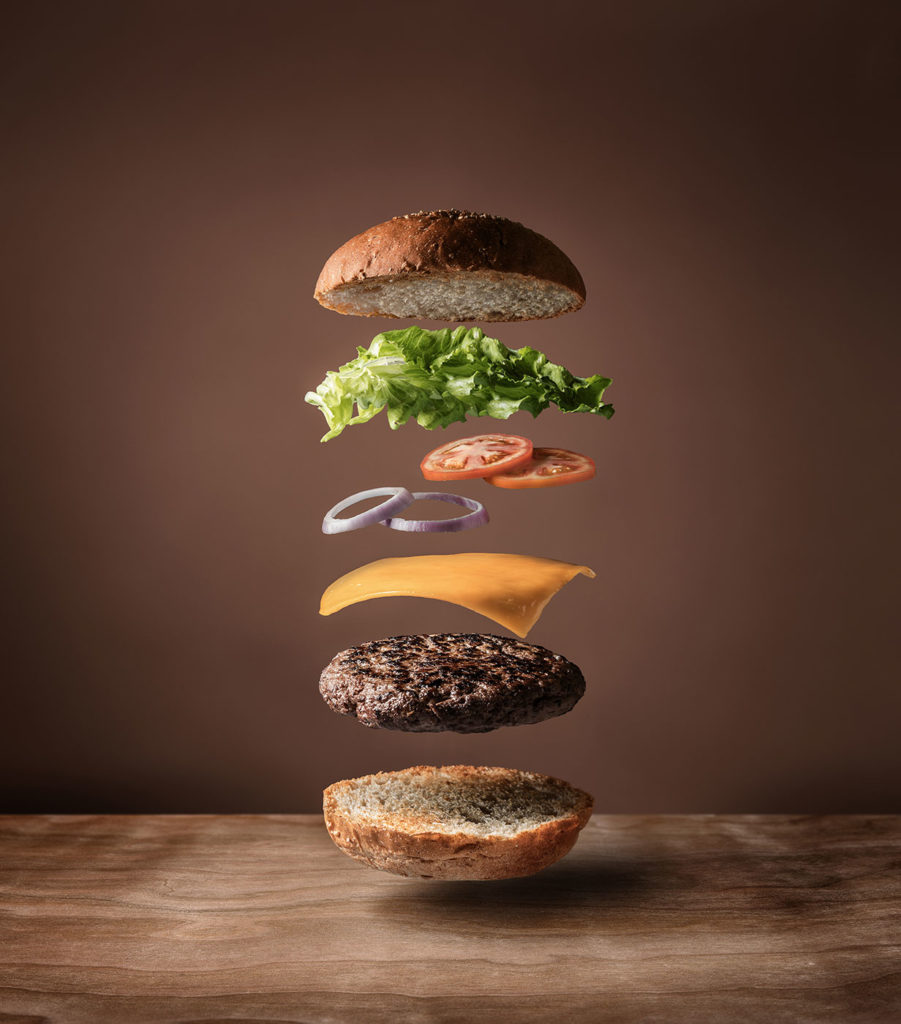 burger with floating ingredients on the wood table background
