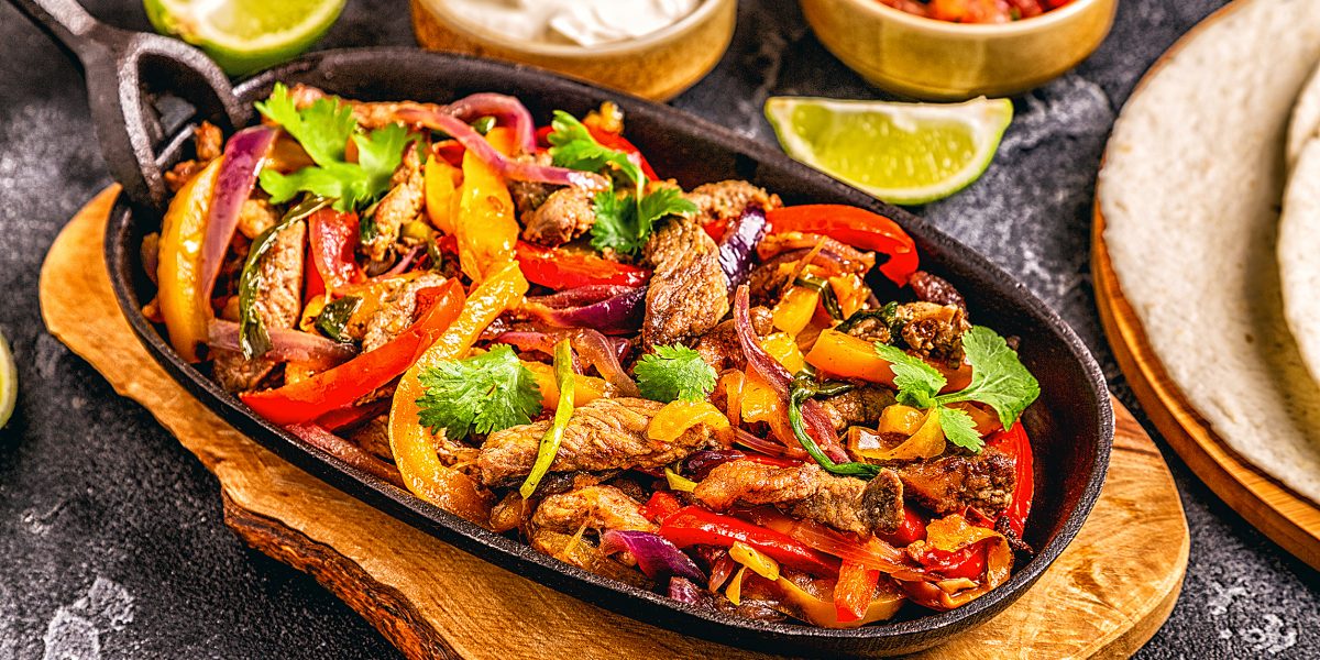 FAJITAS with colored pepper and onions, served with tortillas, salsa and sour cream.