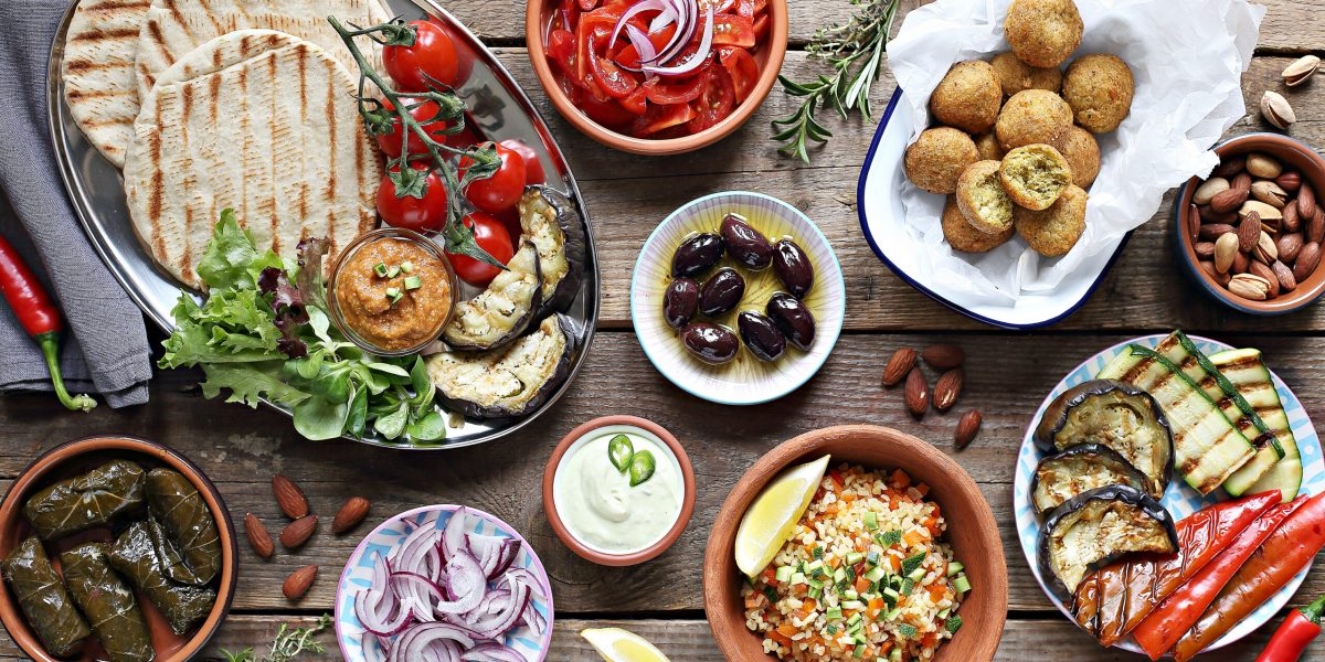 Middle eastern, arabic or mediterranean appetizers table concept with falafel, pita flatbread, bulgur and tomato salads, grilled vegetables, stuffed grape leaves,olives and nuts.